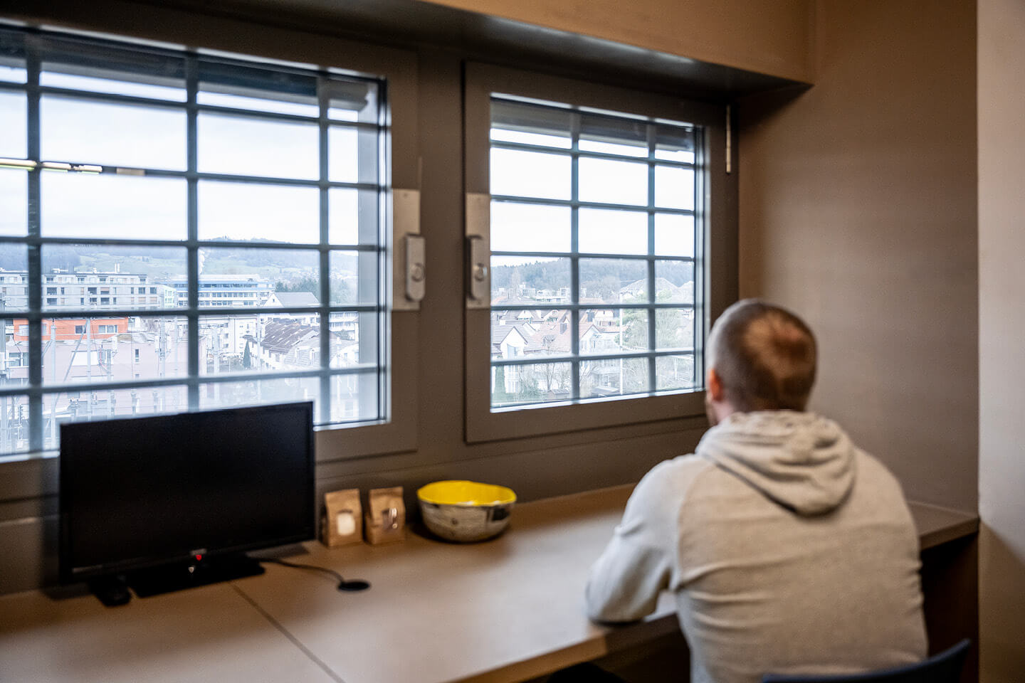 Inhaftierter blickt aus dem Fenster seiner Zelle auf die Stadt hinaus.
